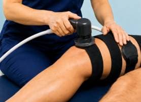 Physiotherapist treating a patient's leg with an FMS magnetic stimulation device at Vyana Ahmedabad