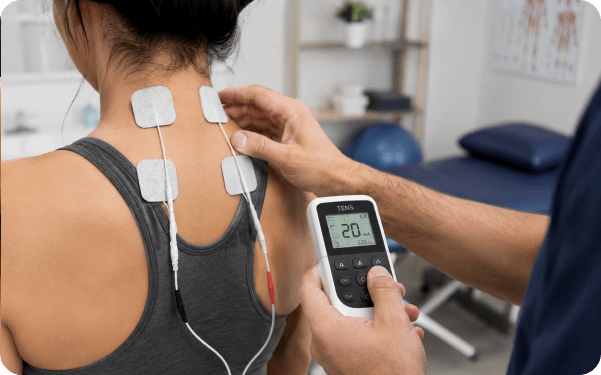 TENS electrode pads on a patient's neck and upper back while the physiotherapist adjusts the TENS unit