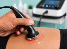 Physiotherapist treating a patient's knee with a TECAR therapy device at Vyana Ahmedabad