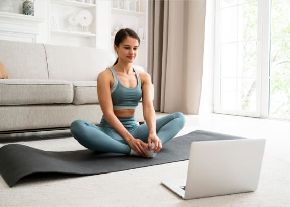 Woman practising yoga with a laptop guided session