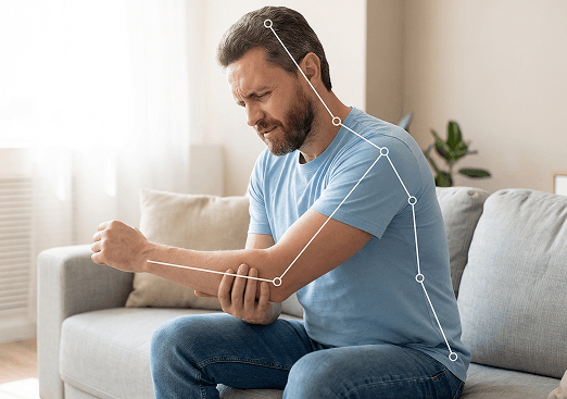 Man sitting on a couch holding his elbow in pain